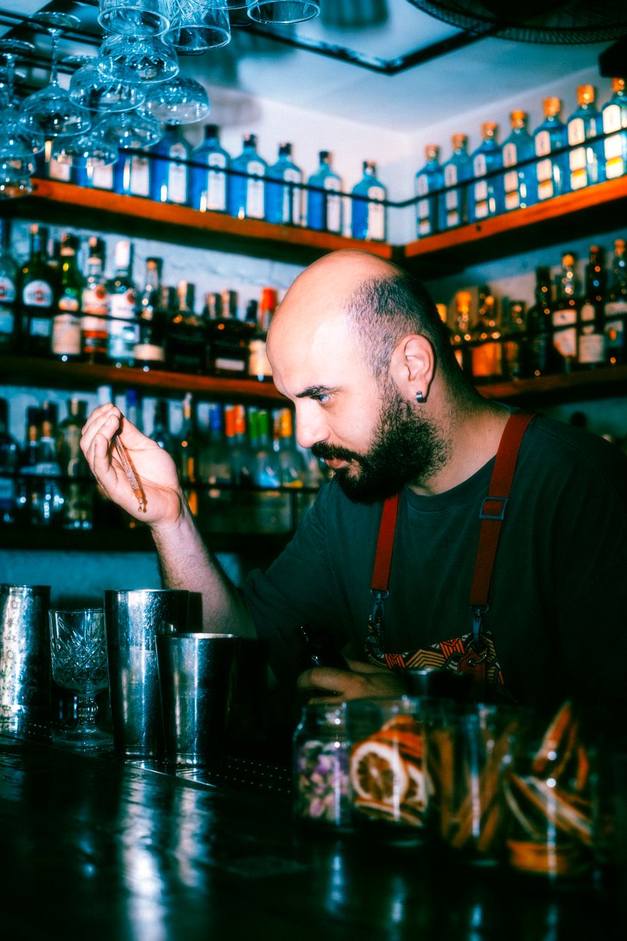 A bartender at work with shelves of bottles behind