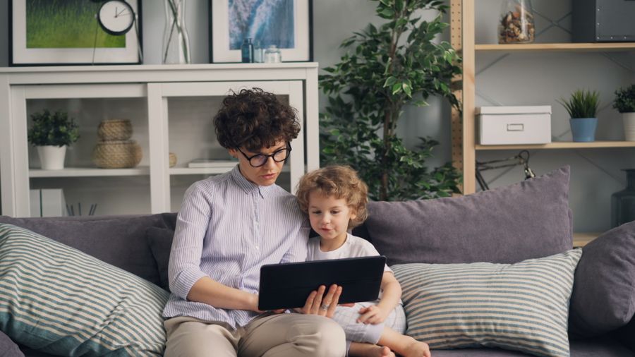 A parent and child using a tablet together on the couch