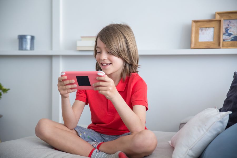 A kid playing a game on a tablet on the couch