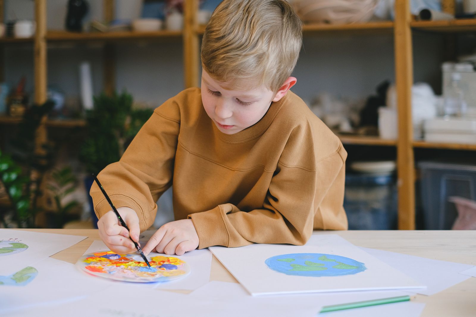 A kid painting a globe on a big sheet of paper