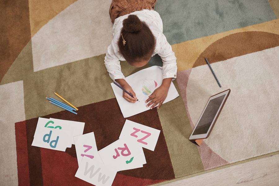 A kid drawing letters with colored pencils