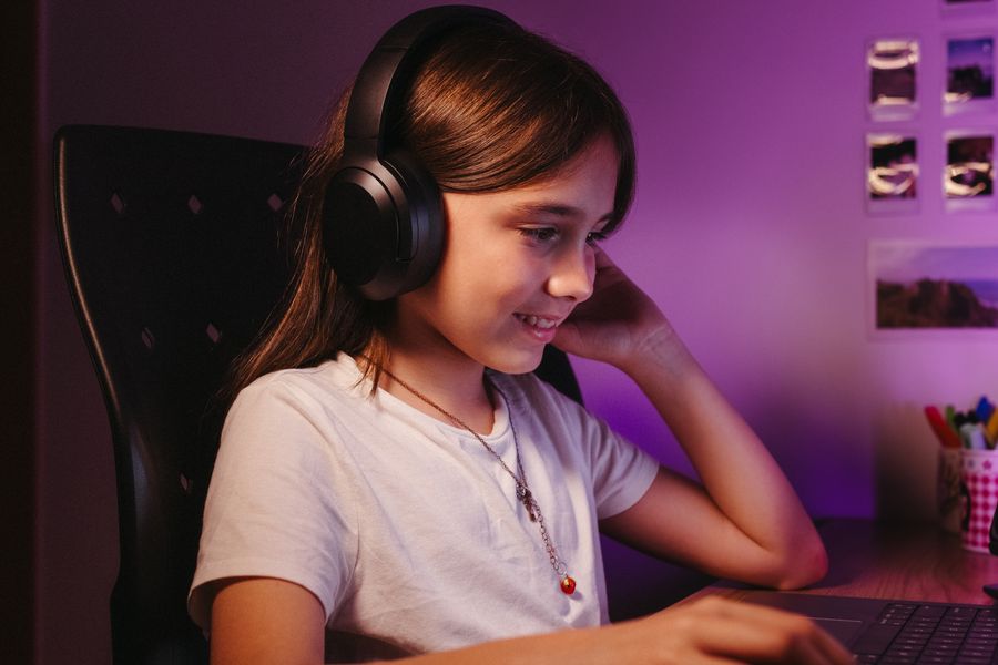 A kid focused on a laptop with headphones at home