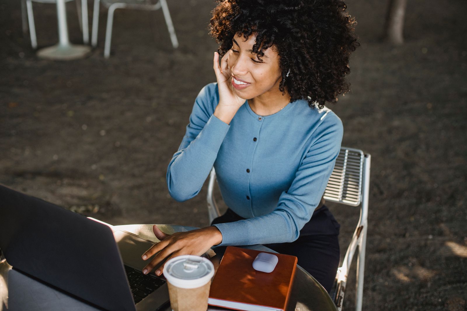 A woman building outdoors with a laptop and coffee